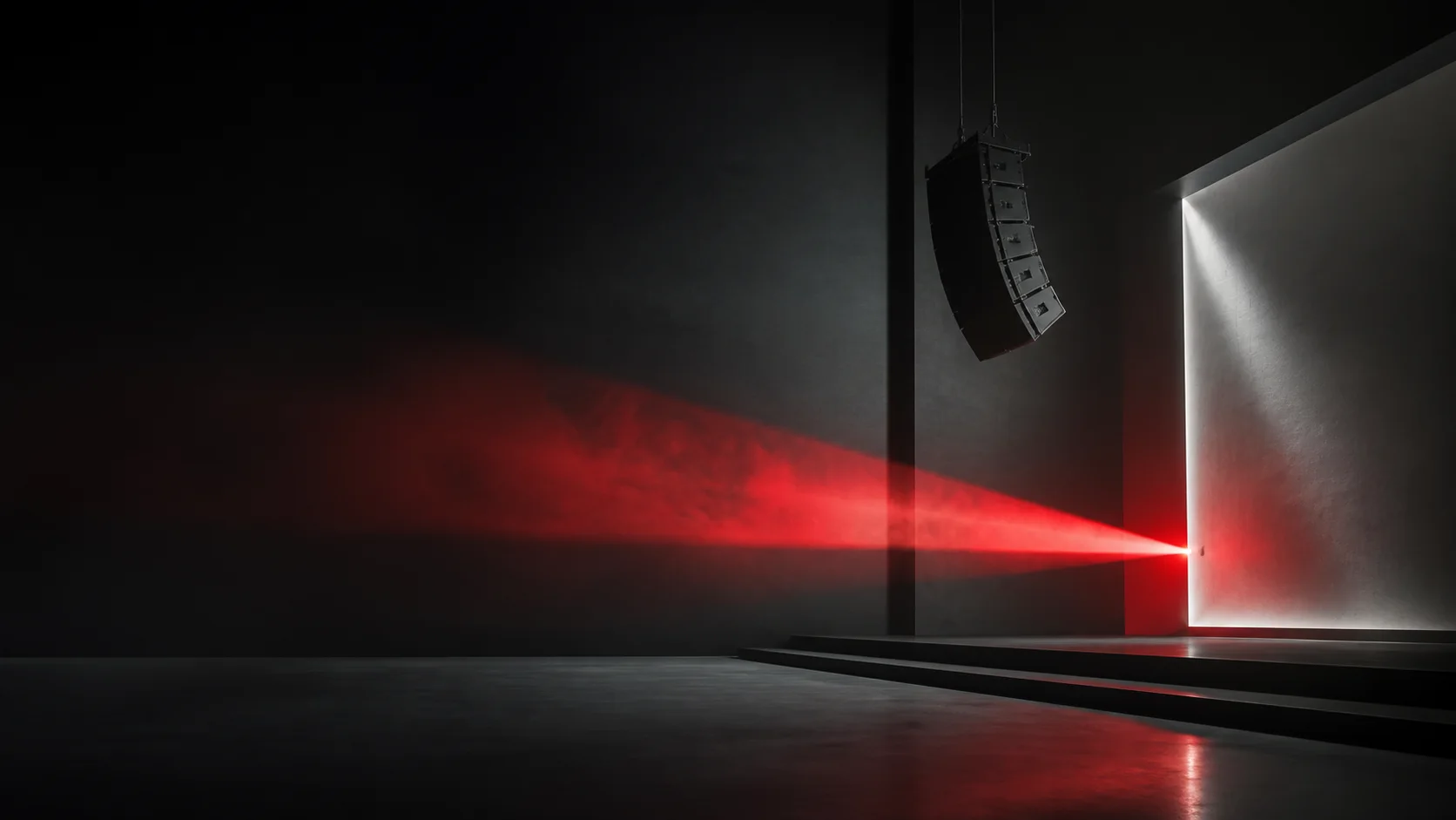 Red beam of light crossing a dark architectural stage with a suspended speaker